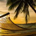 Hammock silhouette with palm trees on a beach at sunset